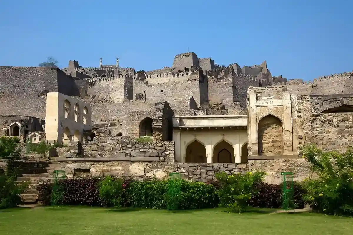 Golconda Fort archeological site in Hyderabad—ancient stone structures, arched pavilions, and manicured green lawns of the historic fort complex.