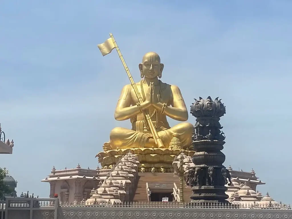 Statue of Equality (Ramanujacharya Statue) in Hyderabad—the massive golden sitting statue of Sri Ramanujacharya atop a carved stone temple base under a clear sky.